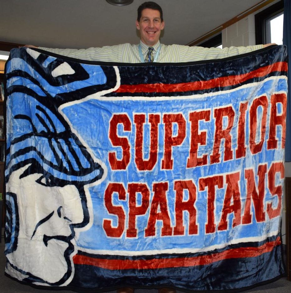 Head Principal Greg Posewitz poses with one possible design for this years Spartan Blanket on Wednesday in his office.