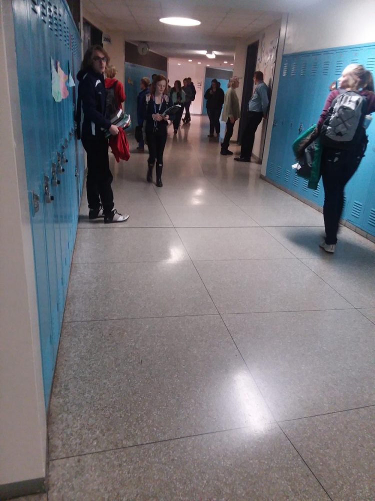 Students walk by Campbells class hearing music

