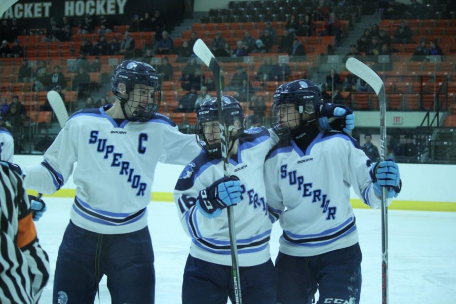 Seniors Max Plunkett, Tucker Stamper and junior Taylor Burger celebrate after Stamper’s goal in the first period. The Spartans lost 3-4 against Eau Claire North in overtime last Saturday at Wessman arena. 