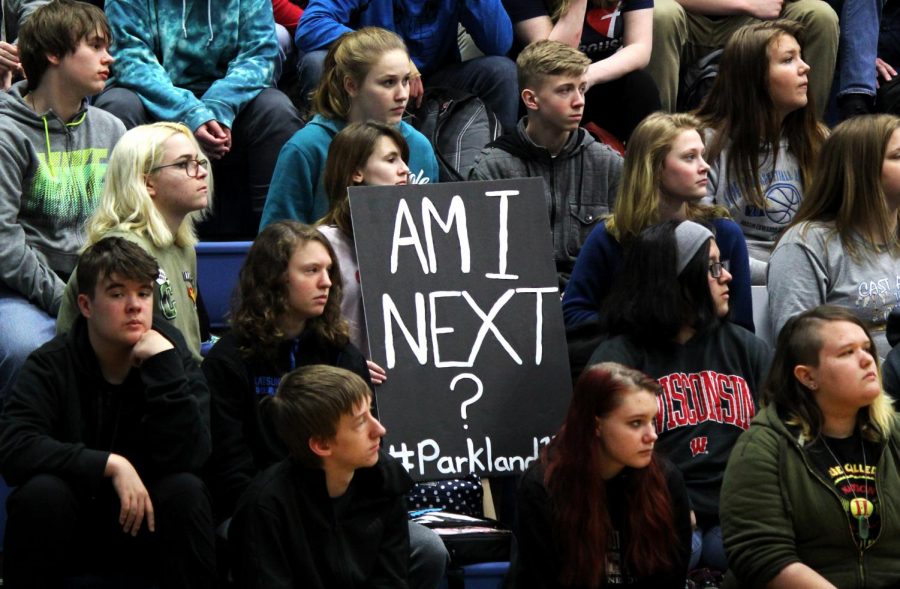 Freshman Abigail Bourque holds a homemade sign during the moment of silence in the gym on Friday.