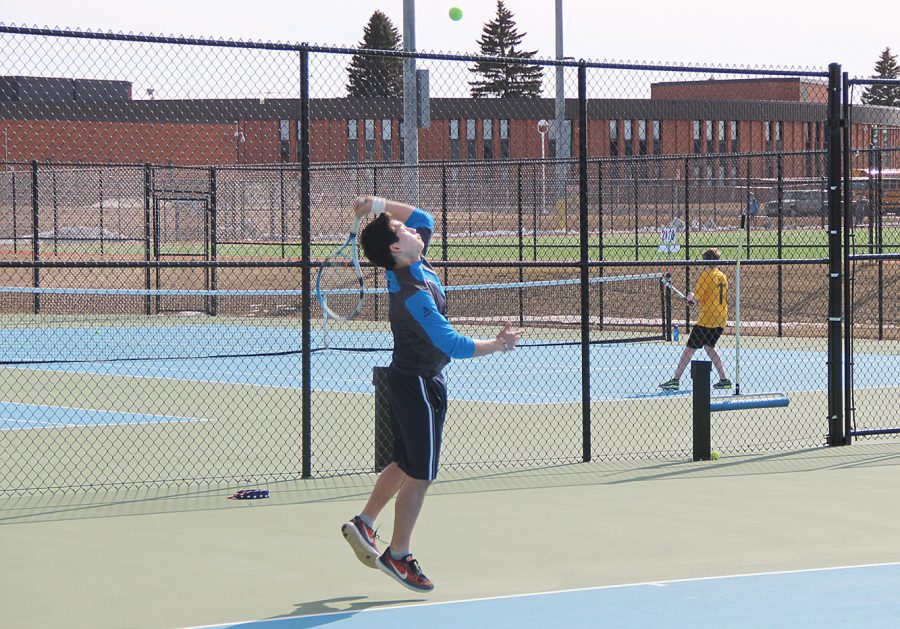 Senior Minjune Jang jumps to serve the tennis ball during his game on April 20.

