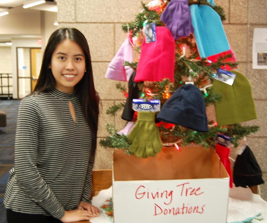 Senior Truc Nguyen poses by the Giving Tree on Dec. 20 during 5th hour in the Library Media Center.