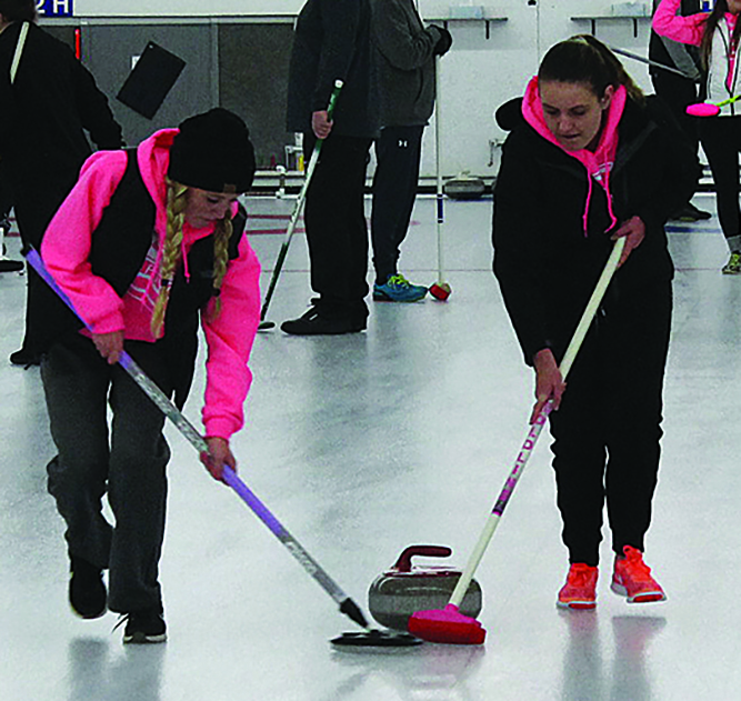 Freshman Emma Sislo (left) and senior Heidi Gondik sweep the rock toward the house at the Superior Curling Club at the Head of the Lakes Fairgrounds Nov. 28. Their team of five competes against more experienced teams weekly. 