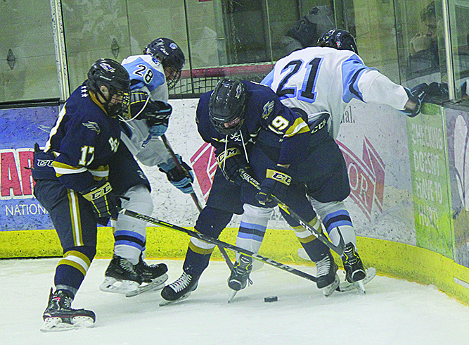 Junior T.J. Sitek (28) and senior Trevor Dalbec (21) grapple for the puck with Hermantown players late in the third at Wessman Arena last night. The final score was 6-0 in favor of the Hawks.