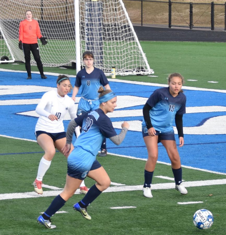Senior Brooke Olson (20) front, sophomore Hannah Drake (8) behind, freshmen Tatum Williams (15) right, Junior Jillian Reuille (goalie) defend their goal from Hudson as sophomore Reuille encourages them at the at the NBC Spartan Sports Complex on April 19. Their efforts were for not as they still lost 0-10.