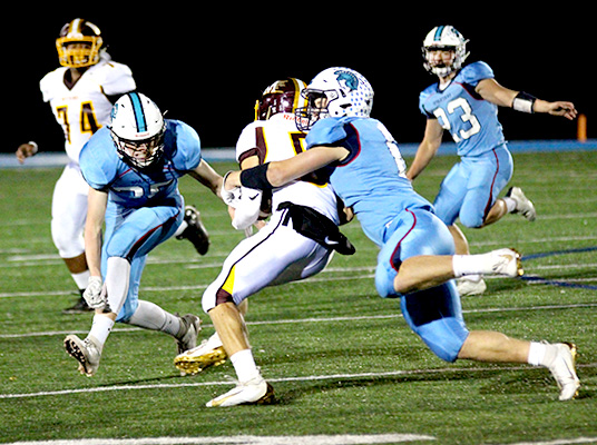 Senior Jarrett Gronski (6) takes down Menomonie’s David Barthen (5) as senior Will Schorr (35) moves in on the play in the third quarter of a 14-13 victory at the NBC Spartan Sports Complex Oct 4. Spartan’s senior Caden Stone (23) pursues the play.