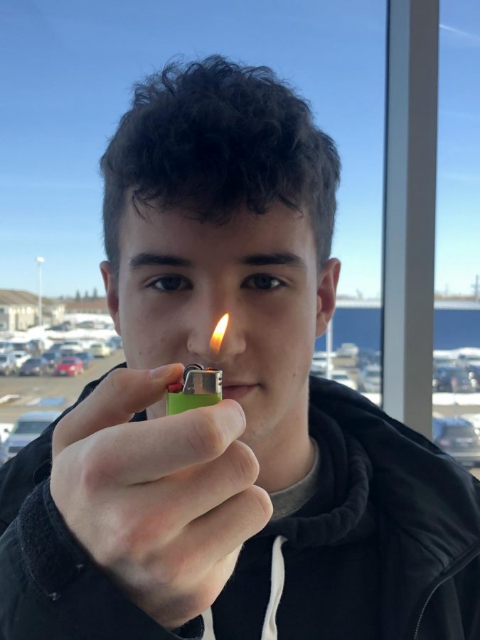 Junior Kaden Radich looks at the flame from a lighter on the second floor hallway balcony on Mar. 6. Local fire officials stress the importance of working smoke detectors in houses. 