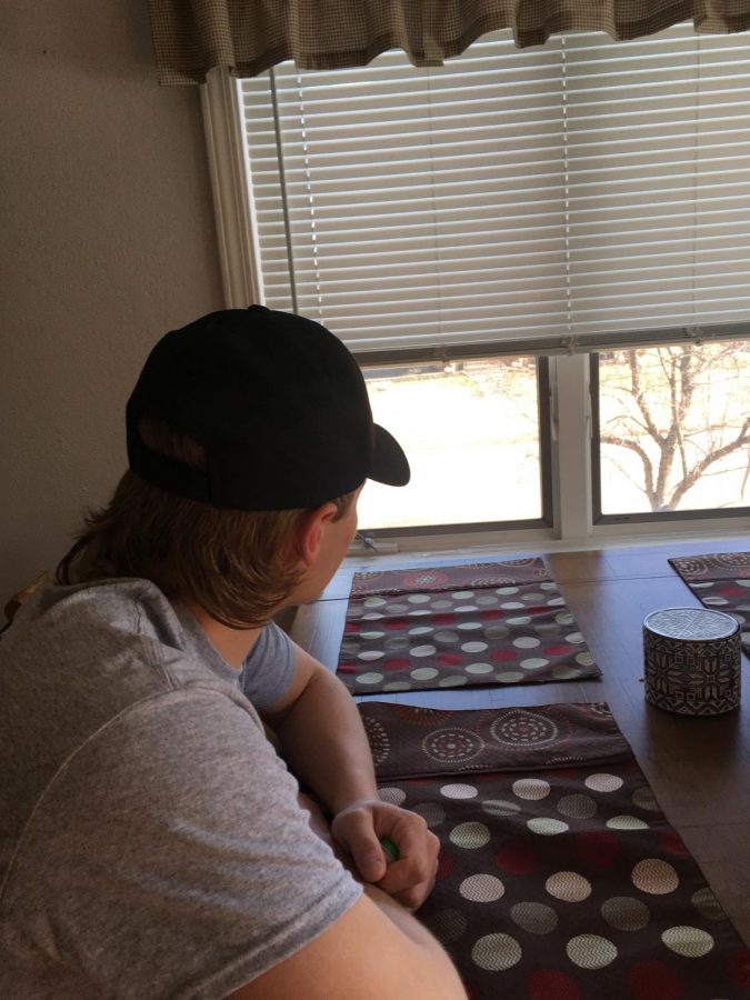 Senior athlete Brennan Morrissey looks outside at a sunny afternoon from his dining room table.