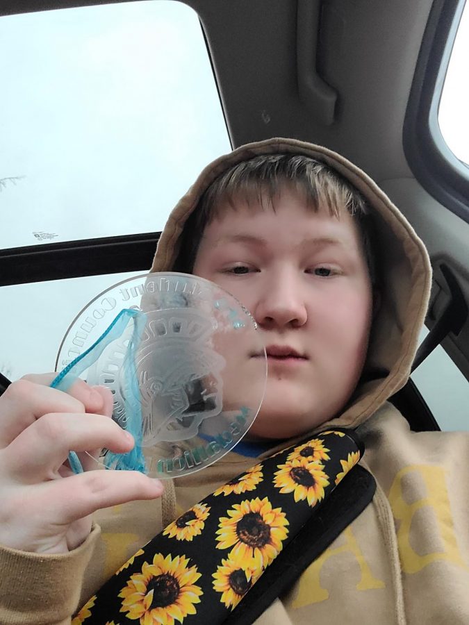 Freshman Nathan Olson is holding the Medallion that he found during the 2020 Snow Week Medallion Hunt.