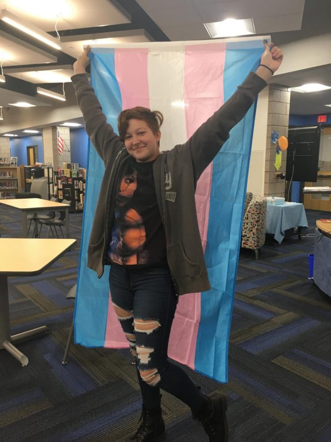 Junior Xen Brown stands with their transgender pride flag.