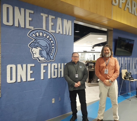 Food Service Director Jamie Wilson and Principal Rick Flarhety posing in front of the “One Team One Fight” wall. Wilson and Flaherty played important roles in the decal project.