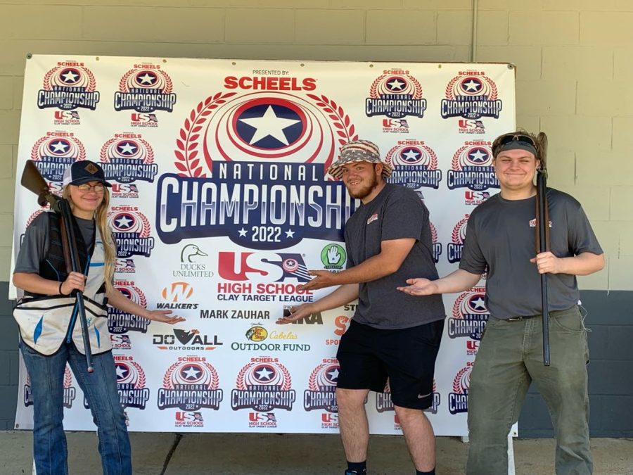 Junior Abby Peterson, and Alumni Justin Kimmes and Ethan Peterson standing in front of the National Clay Target League Championship banner on July 9-16, 2022 at Cardinal Shooting Centre, Marengo, Ohio.