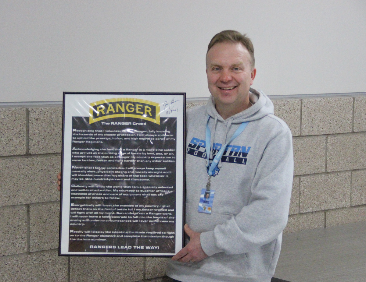 Civics teacher James Hogan holds the Army Ranger Creed sign outside room 3156. Nov. 21, 2023