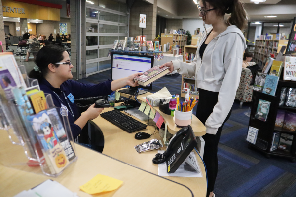  Librarian Assistant Malita Villamayor checks out a book from Junior Chloe Neylon.
