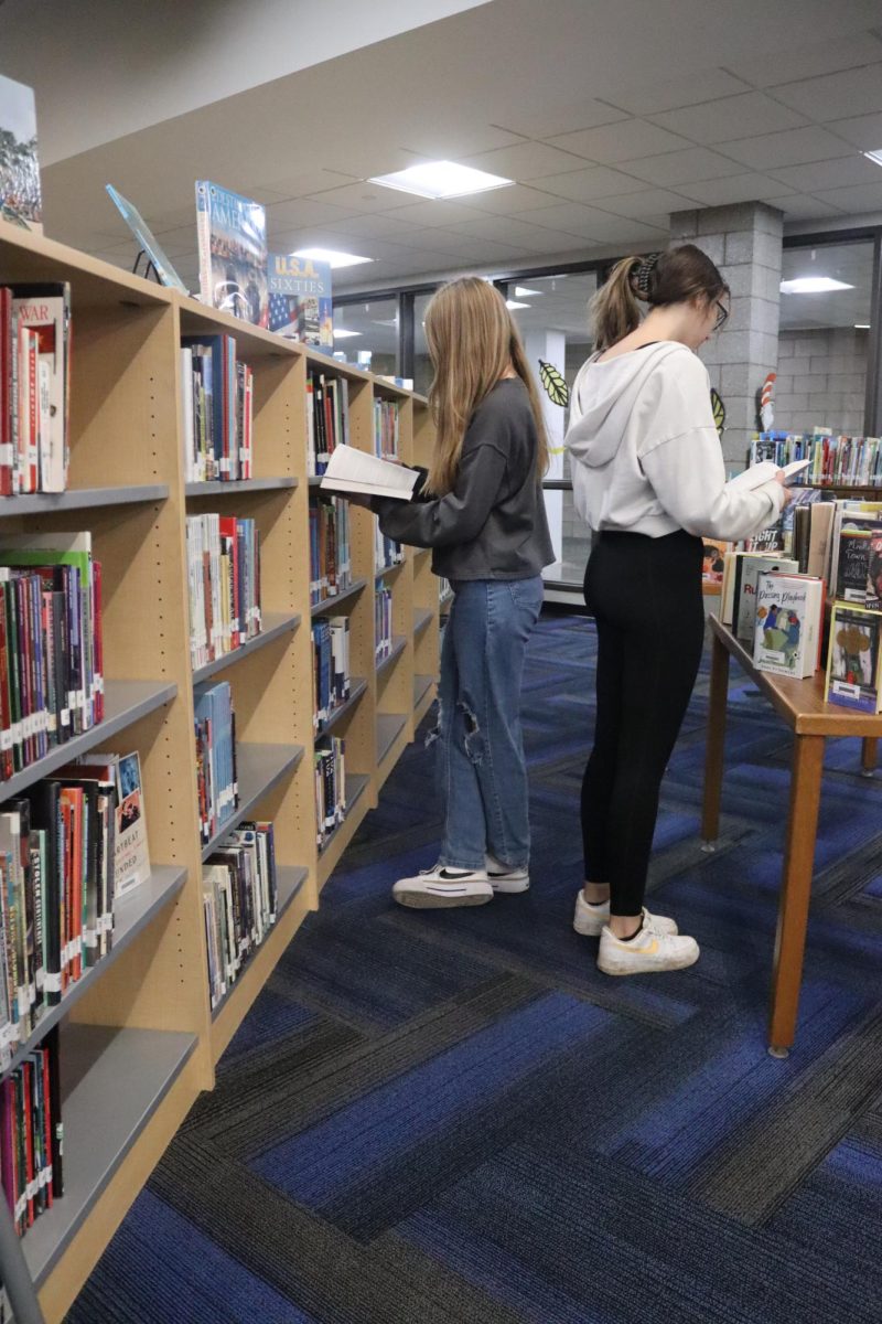 Juniors Mariah Miller and Chloe Neylon look at books in the library.