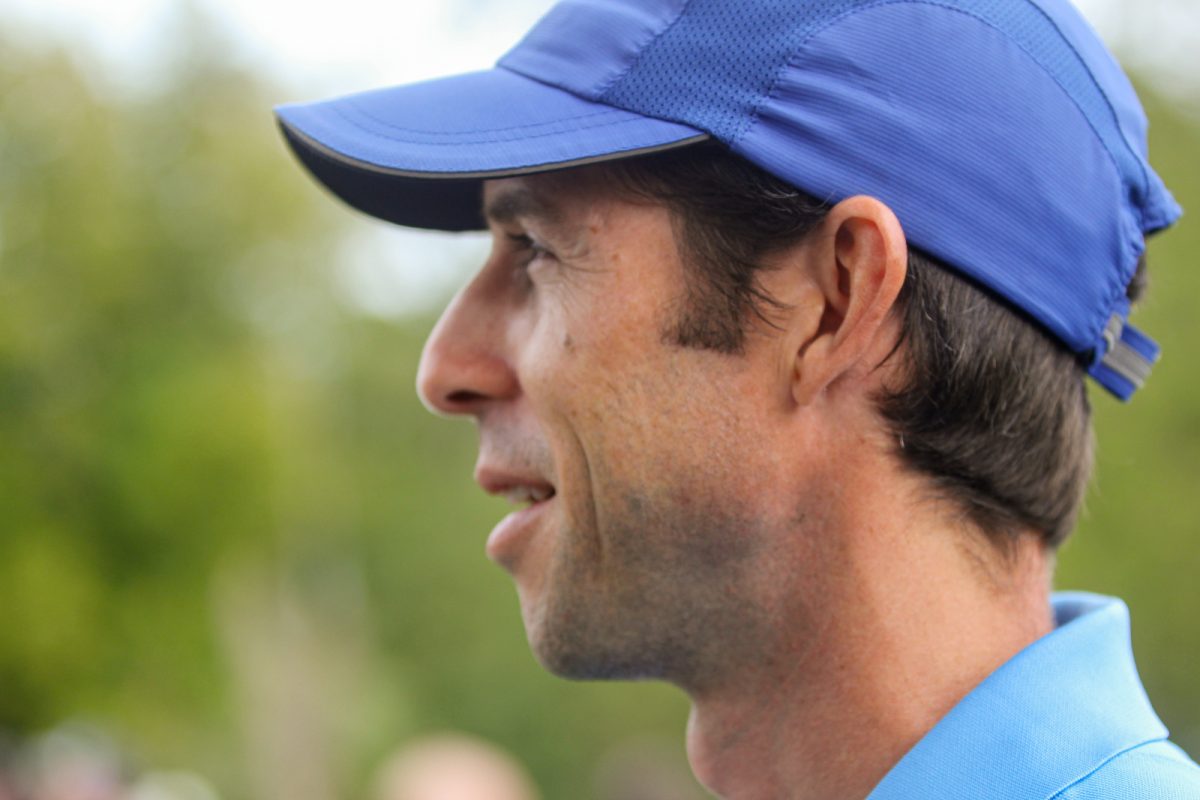 Cross country coach Lee Sims smiles as he watches a race during a home meet at the Pattison Golf Course on Sept. 7, 2023.