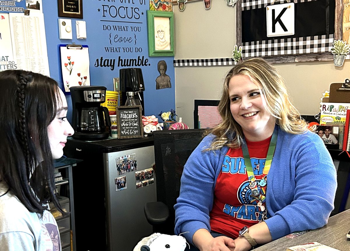 English teacher Emily Kelly talks to junior Victoria Nelson in Kelly’s room on May 3, 2024. Nelson holds a stuffed opossum that Kelly has for students to hold.