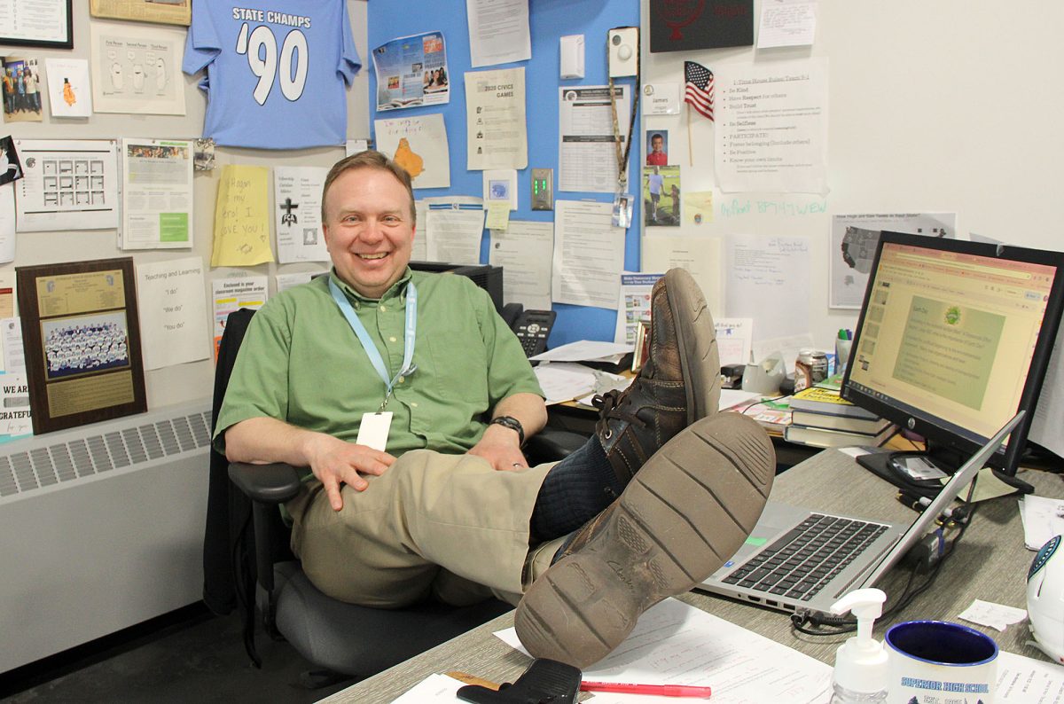 Social studies teacher James Hogan laughs as he poses for a photo at his desk in his classroom on May 9, 2024.