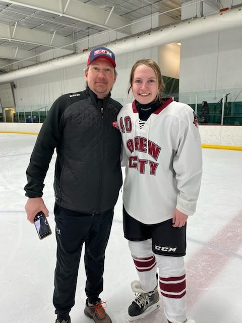 Scott Olson poses with daughter Grace Olson at hockey rink. 