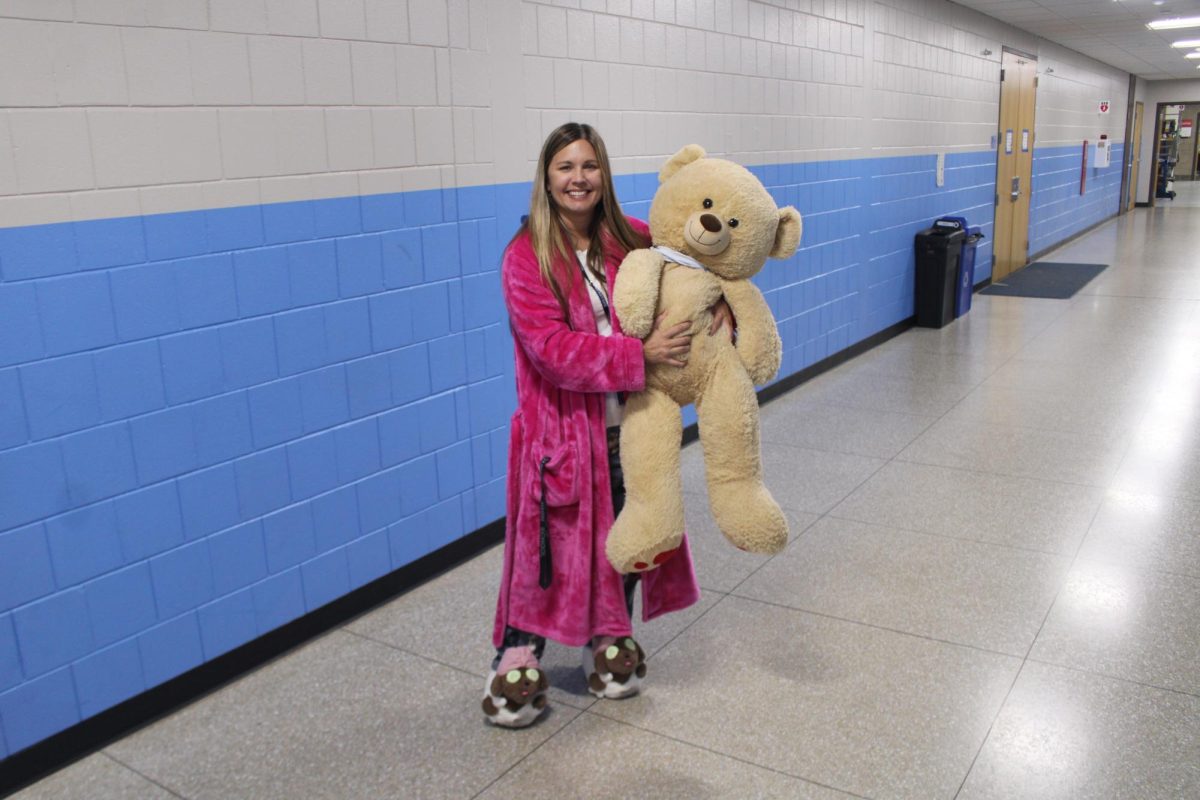 Gym teacher Deana Wells poses in her pajamas to show her school spirit for homecoming in front of her office in the gym hallway. Oct 2, 2024.  