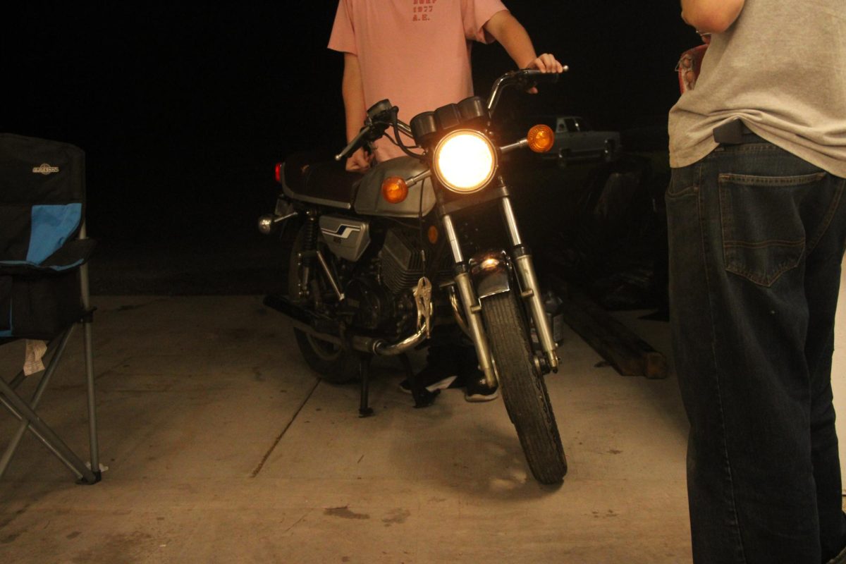 Junior Hunter Sanders stands over his motorcycle outside of senior Josh Hersted’s garage on Sept. 14.
