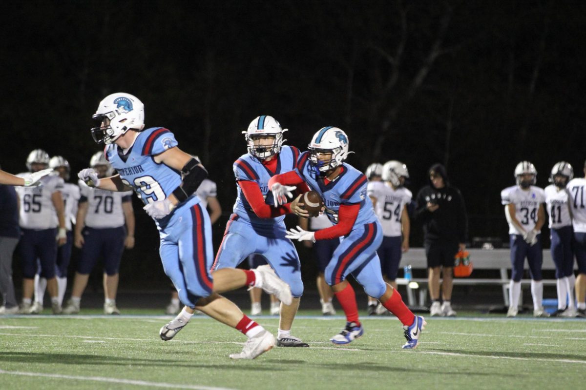 Senior quarterback Tanner Leno (13) hands the ball off to Junior running back Taynum Clark (3) in the homecoming football game. The game took place on Oct. 4, 2024