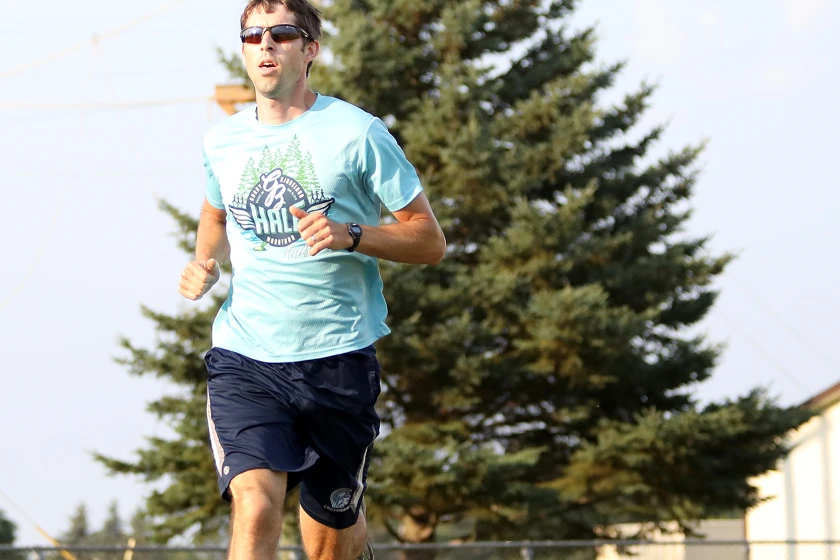 Cross country coach Lee Sims wins the first mile of the mini track meet next to Wessman Arena on Tuesday, July 23.