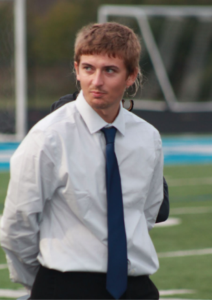 Assistant soccer coach Evan Ridd listens to the starting lineup of the boys varsity soccer team at the NBC Spartan Sports Complex on Sept. 12. 