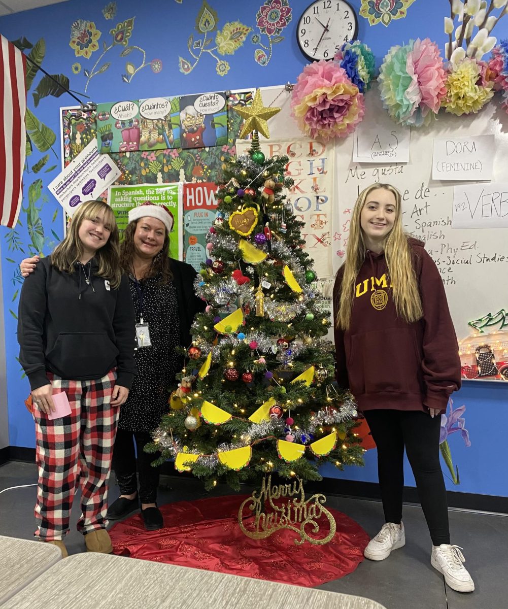 Sophomores Rylee Watschke (left) and Lexi Kaspar (right) pose with their Christmas tree gift to teacher Allison Conley
