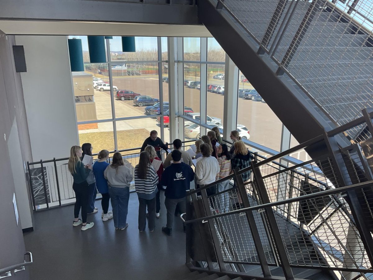 Choir rehearses for their spring concert in the E16 staircase Wednesday April 16. Choir teacher Tim Delnay brought the group to the staircase to practice using acousics while singing occapella. 