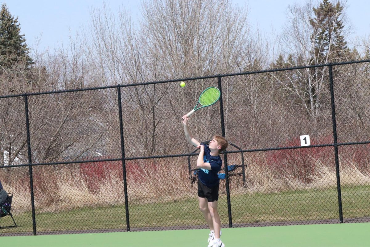 Junior Ty Soderlund takes trophy position as he prepares to serve. The tennis team ended the match with two wins against Ashland and Ellsworth.
