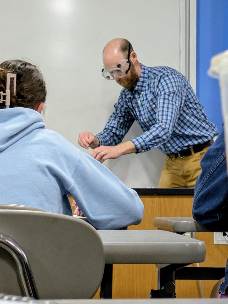 Teacher Tyler Ross pours hydrochloric acid into a buret in Titration demo on May 14, 2025.  The Demo was an introduction into acid base titrations.