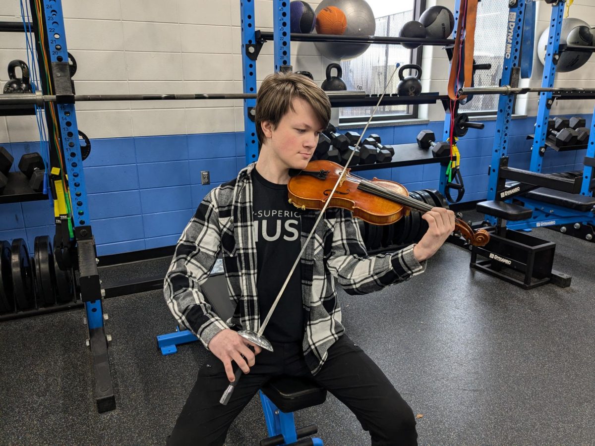 Junior Dillon Blix shows off both his swordsmanship and violin skills in the weightroom where he practices fencing on April 29, 2025.