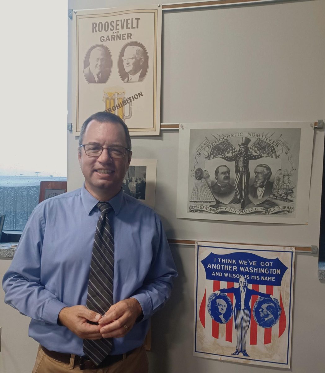 Returning Mock Trial coach Kyle Smith poses in front of history posters in his classroom room 3141 on Sept. 19. He shows off his love and passion for social studies and law which translates into his love for Mock Trial.