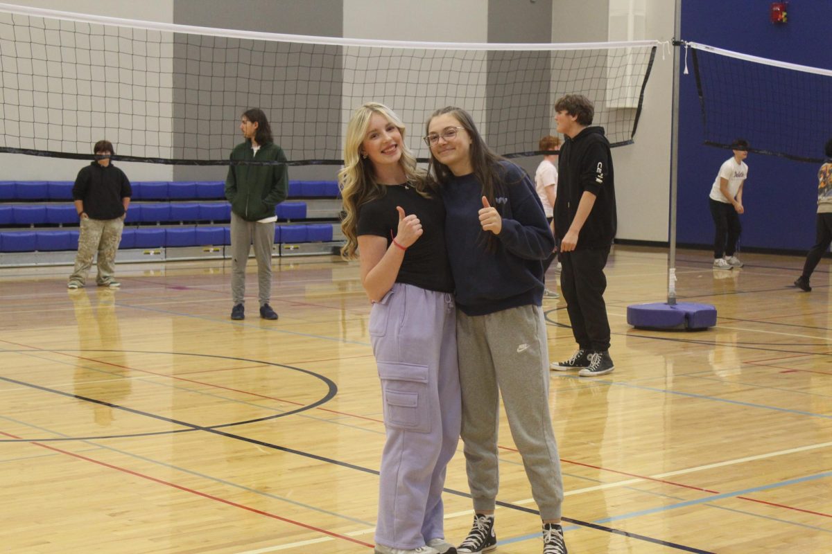 Junior Madeline Manion(left) poses with Junior Lainey Pananen(right) during their Lifetime Fitness & Activities gym class on Oct. 8, 2025. They are playing volleyball for their current fitness unit.