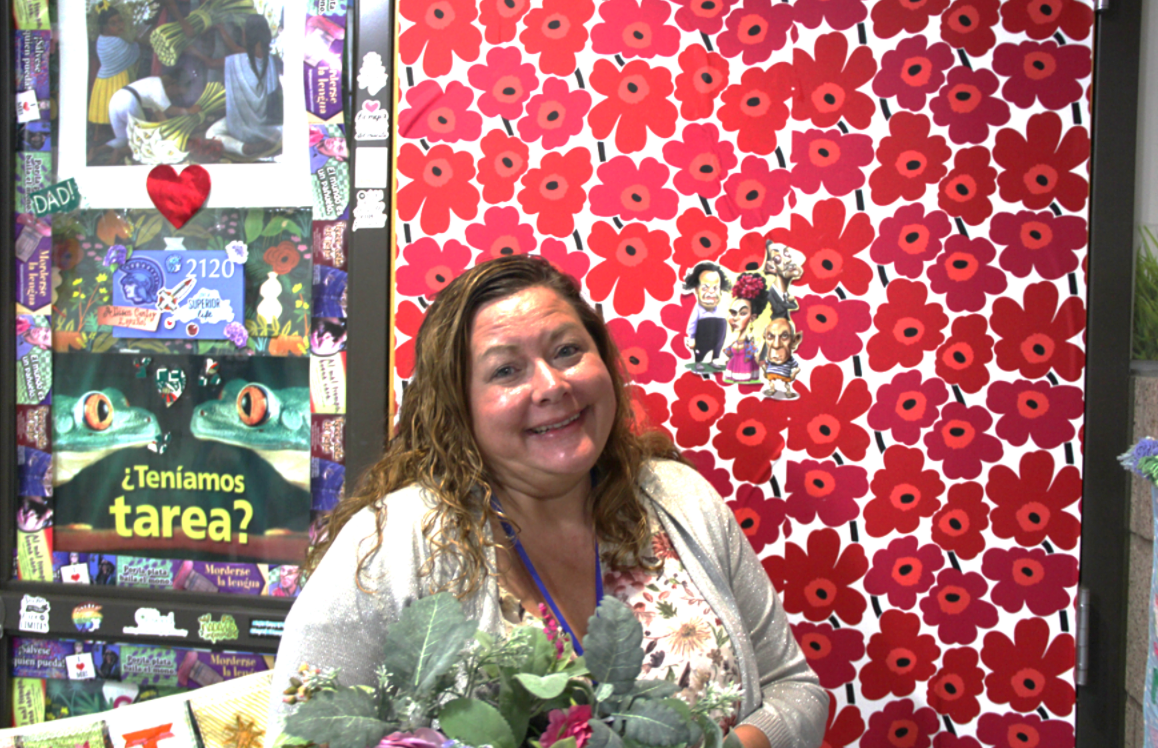 Spanish teacher Allison Conley holds a wreath of flowers in front of her classroom door on Sept. 30. 2025. She shows off her love for colors and patterns through door decorating. 