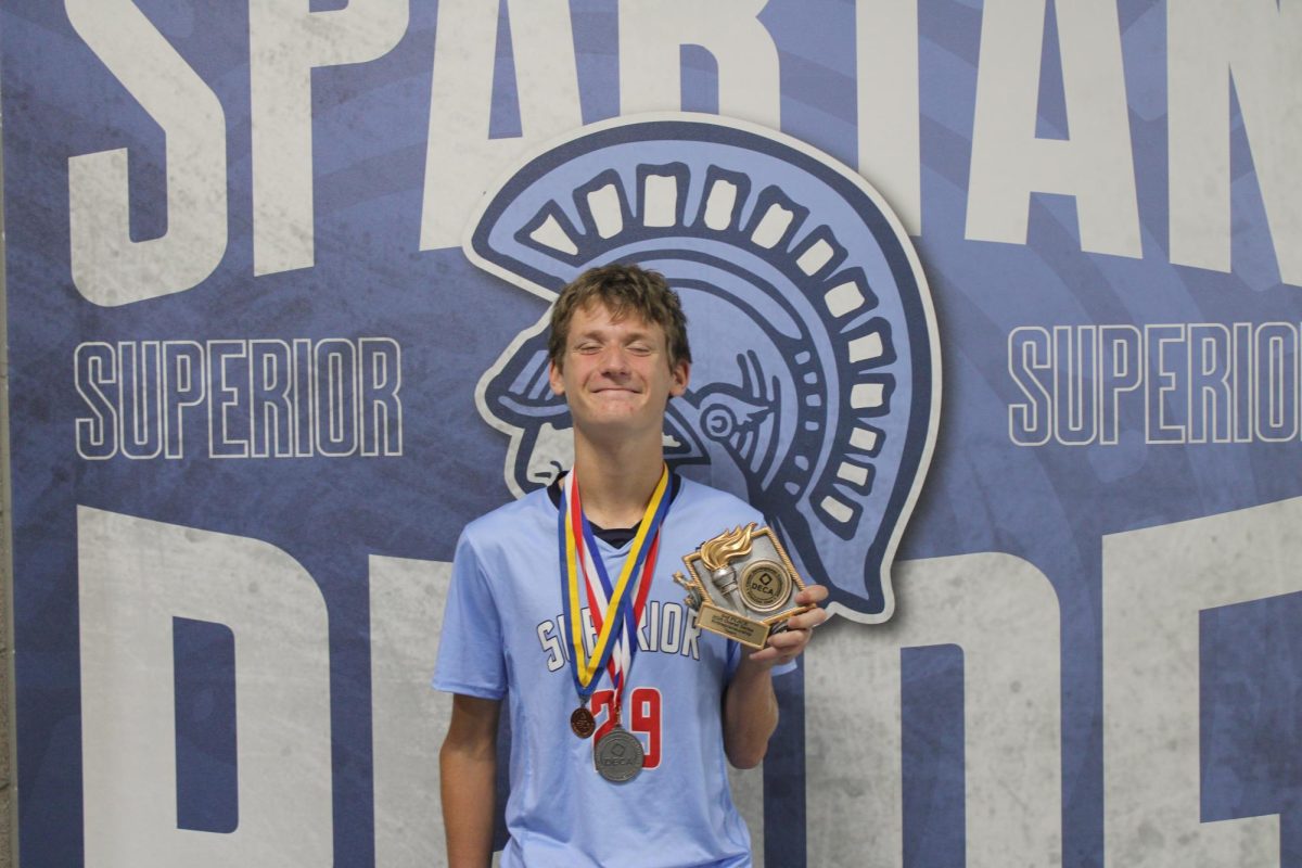 Senior Jack Mueller wears a DECA and FBLA metal, his soccer jersey, and holds a DECA trophy in Superior Highschool, Superior, WI, on Sept. 17th. Jack earned these metals and his varsity jersey all at once, showing his ability to juggle all of his responsibilities. 

