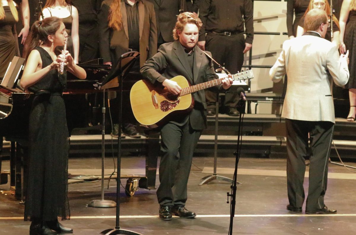 Seniors Lili Sakuray and Gabe Killian play the flute and guitar while Timothy Delnay, the choir teacher, directs “Wreck of the Edmund Fitzgerald” in the Performing Arts Center on Oct. 22, 2025. Sakuray and Killian were one of the main spotlights of the choir concert.
