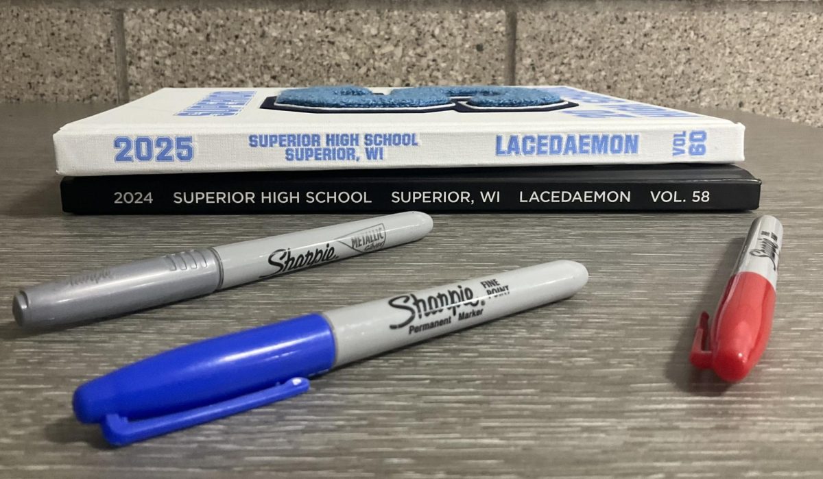 Previous yearbooks stack up in front of sharpies on a table in the second floor hallway. This year’s yearbook will be organized differently to accommodate the large senior class.