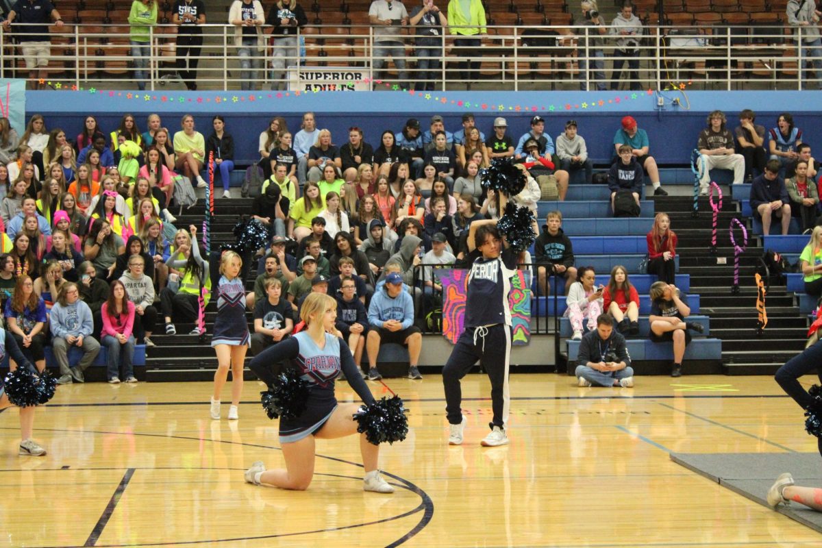 Current cheerleader Joshua Robbins is positioned (To the right, behind the kneeling cheerleader) to start the homecoming cheer performance in the homecoming assembly Sept. 26, 2025.