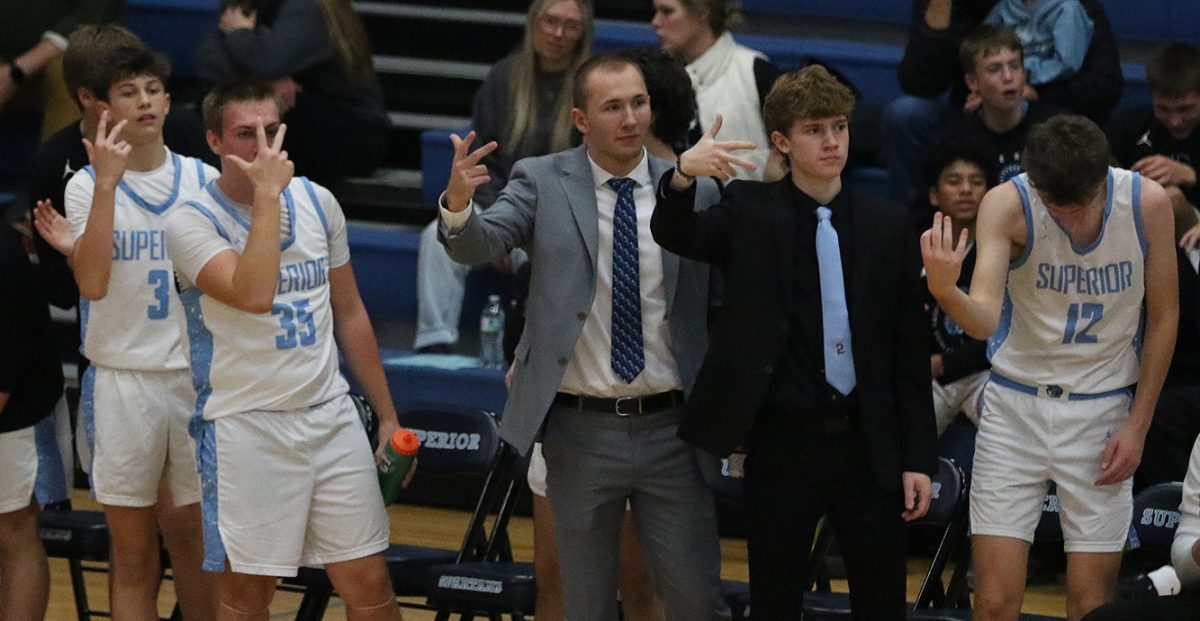 Spartans boys basketball bench including the two players out, senior Drew Eisel (left), and senior Colson Schumacher (right), celebrate after senior Calvin Anderson knocks down a three on Dec. 5. 