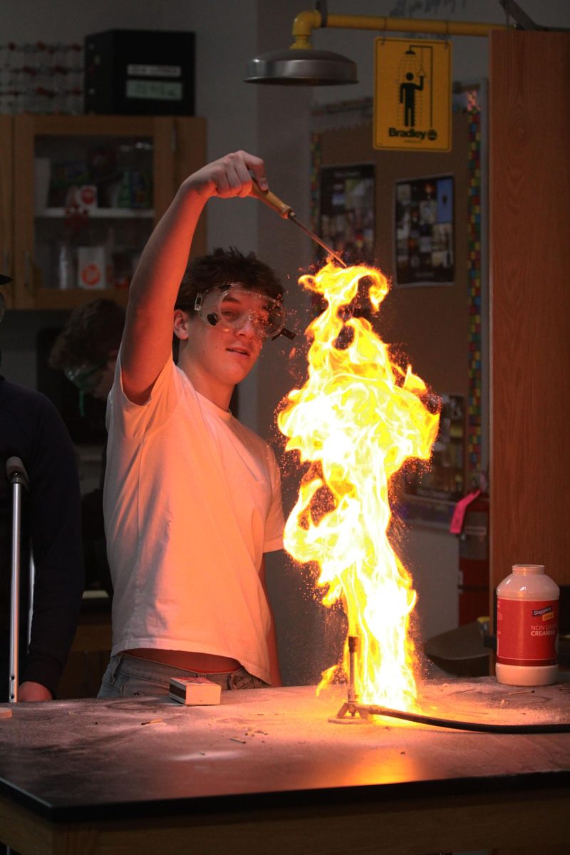 Sophomore Marc Pagnucci pours dairy creamer over a bunsen burner in science teacher Angela Johnson’s chemistry class on Jan 9.  Chemistry is in their reactions unit, so this experiment is used as an example of a combustion reaction. 
