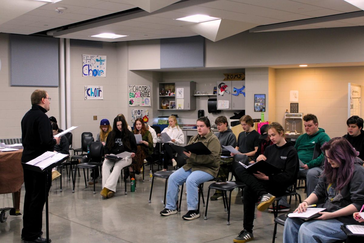 Choir director Timothy Delnay (left) instructs the members of the Spartan Singers on a new language to sing with, for the upcoming Solo and Ensemble performance in Febuary.