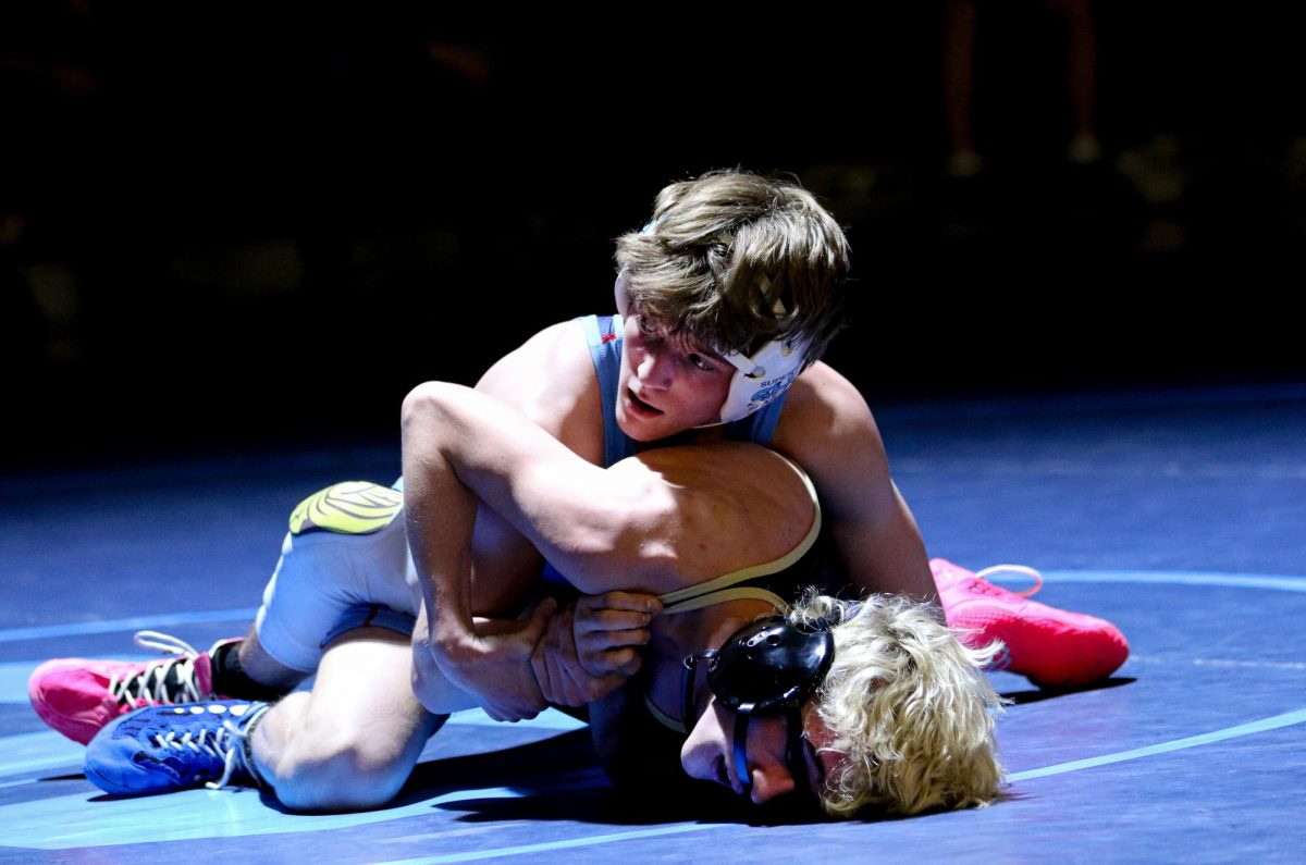 Junior Versii Kavajecz holds down a Hayward wrestler and looks over to coach Nicholas Long on Jan. 8.