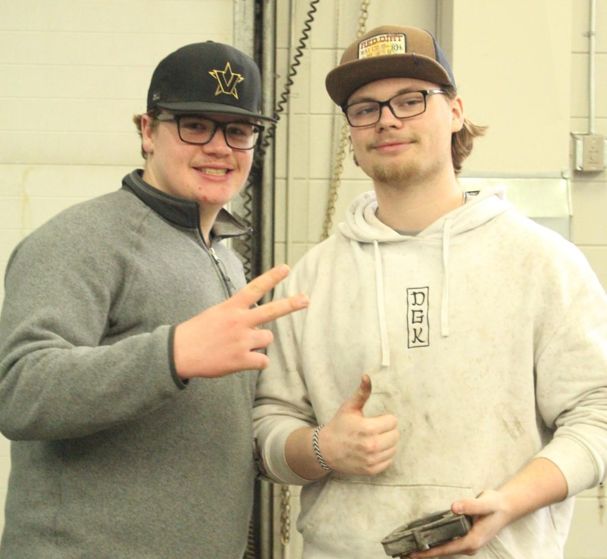 Senior photographer Michael Fiegle (left) poses with his friend and teammate, sophomore Ayden Atchison, in the mechanics room in the Tech Ed wing on March 26.