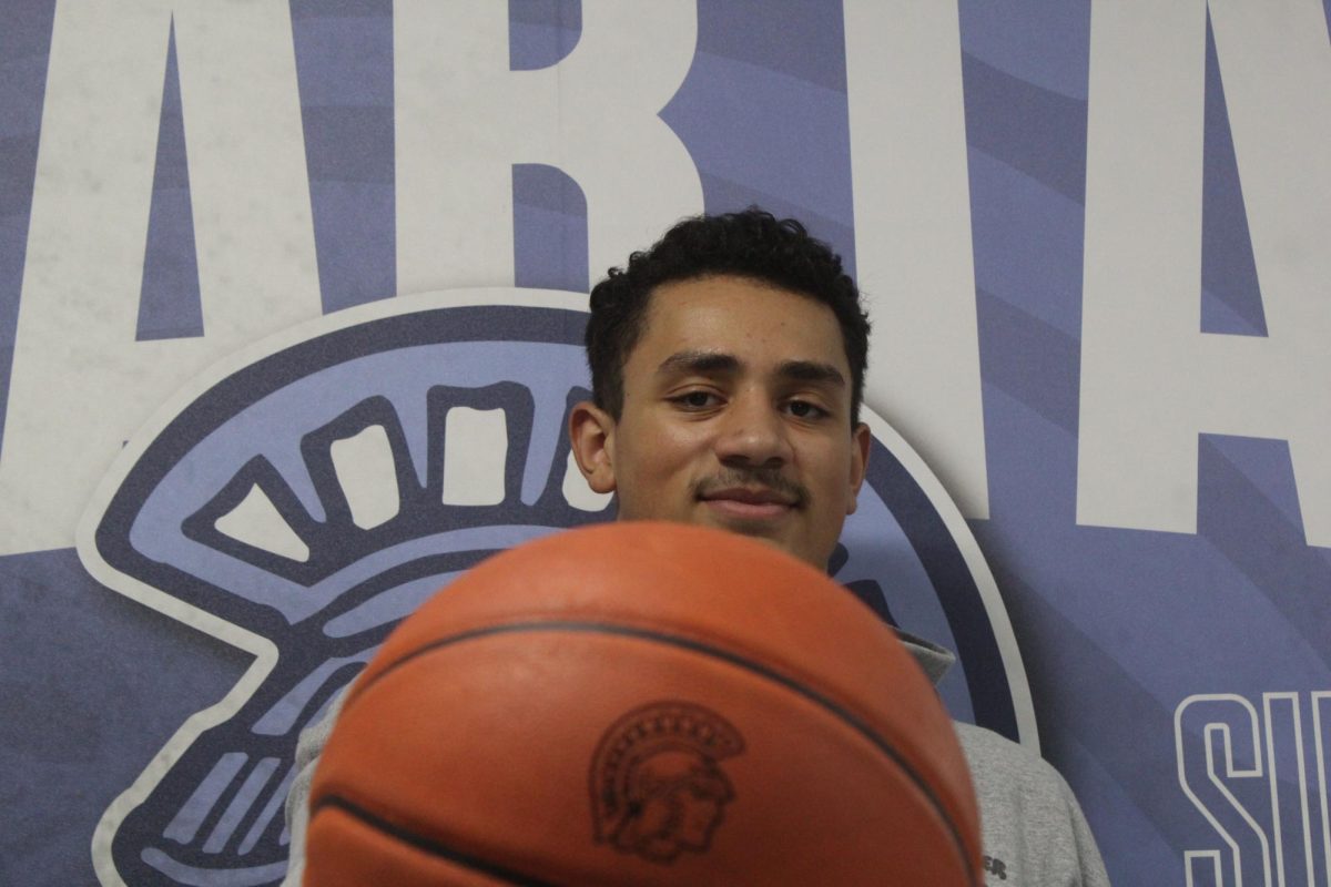 Kaden Covill poses for a photo with a basketball in front of a Spartan backdrop on Feb. 19.
