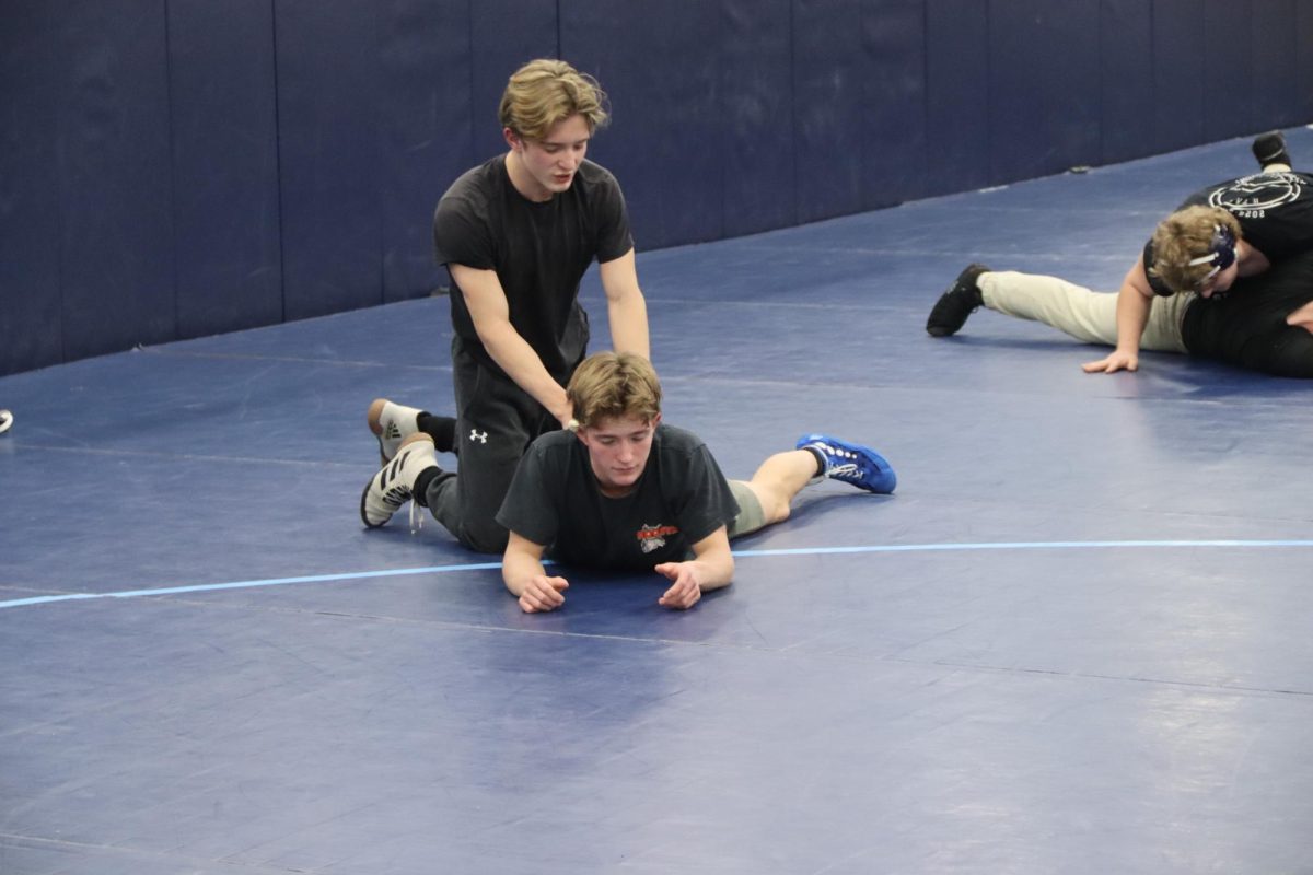 Juniors Exxl (above) and Versii Kavajeecs (below) help each other in the Spartan wrestling room during a practice on Dec. 17, 2025. 