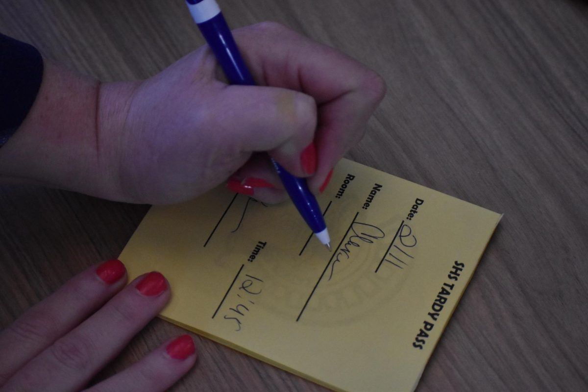 Attendance secretary Elaine Holmberg signs a tardy pass for a late student at 12:45pm on Feb. 11.