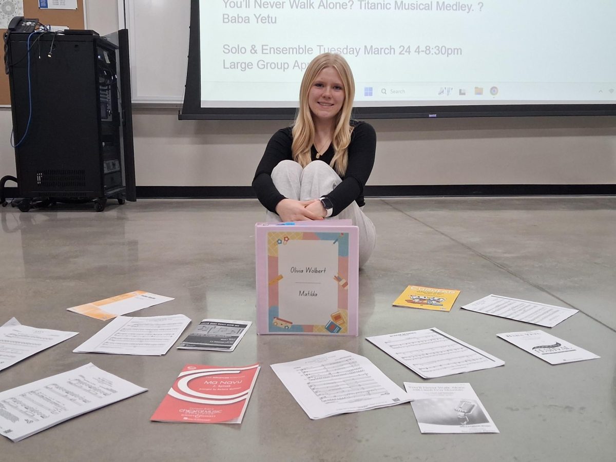 Wolbert sits surrounded by all of her sheet music for solo’s and shows off her musical binder for the play.