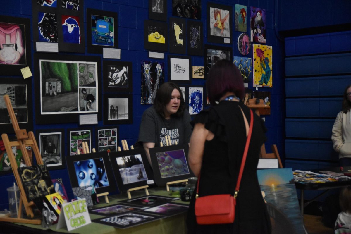 Senior Paige Gross describes her artwork creations to people that visited the Spartan Fiesta on May 6, 2026. There was a variety of senior artwork showcased in the Spartan Fiesta located on the walls of the Spartan Arena to show for the people visiting. 